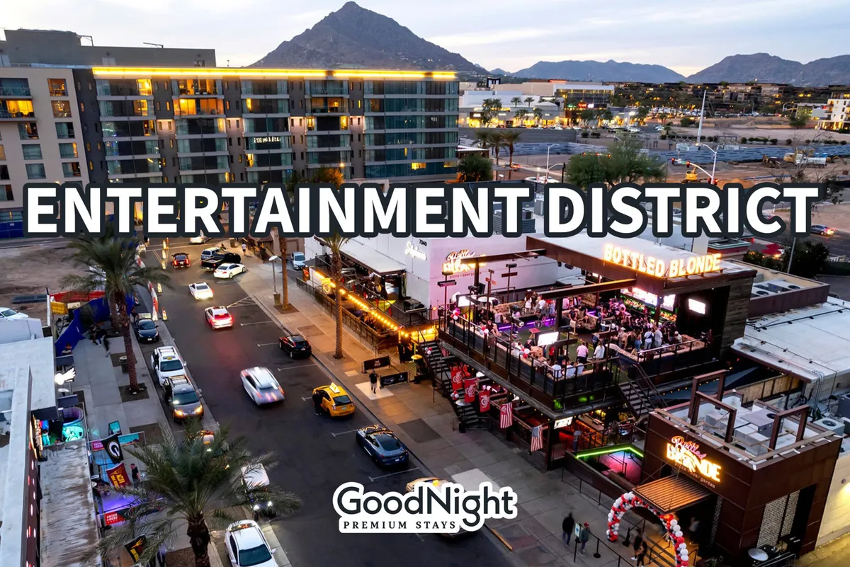 A bustling street lined with entertainment venues and lively crowds, set against a backdrop of mountains. The image presents a vibrant, walkable urban environment with dining, shopping, and social opportunities steps from the front door.