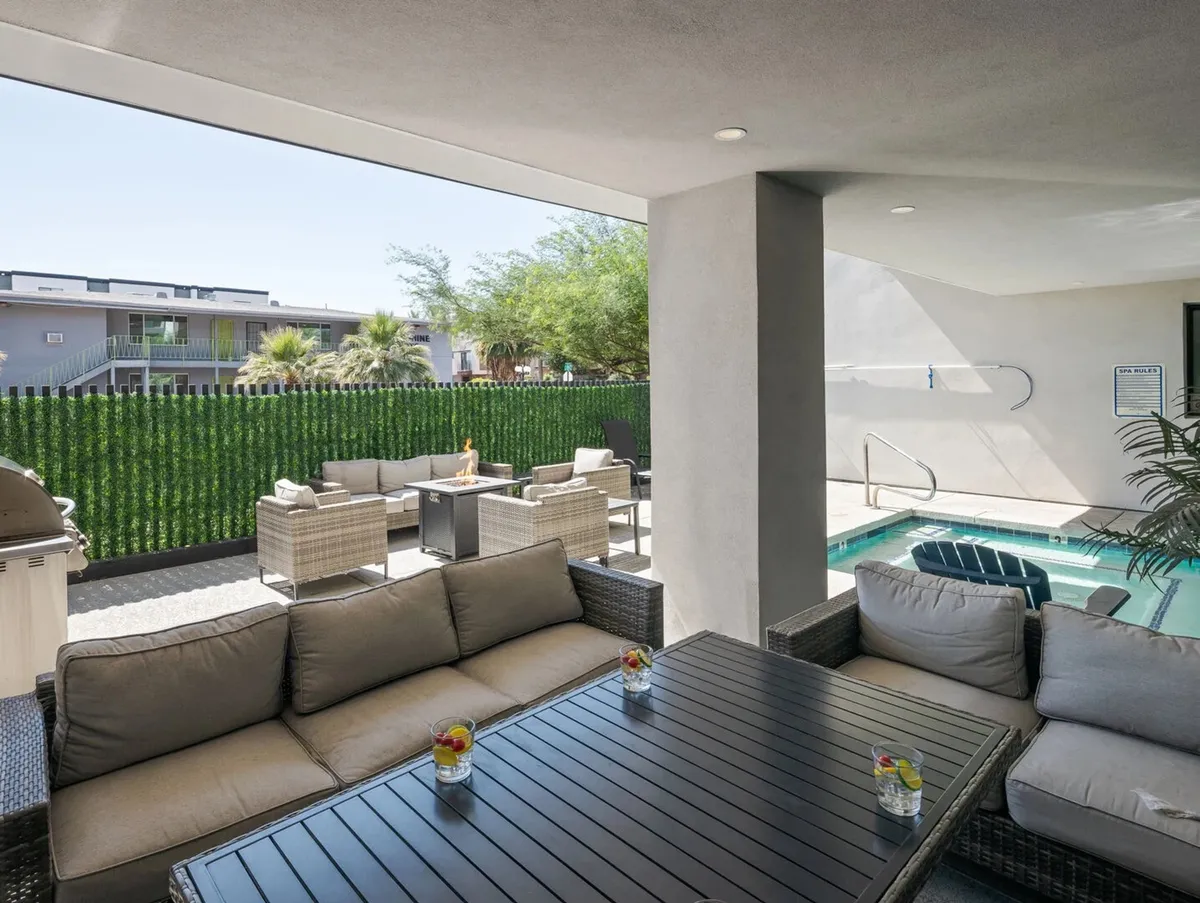 An inviting outdoor seating area set beside a sparkling swimming pool, surrounded by lush greenery. The comfortable lounge chairs and shaded areas create a relaxing ambiance, perfect for both social gatherings and tranquil moments by the water. The view hints at sunset lighting, enhancing the sense of resort-style leisure.
