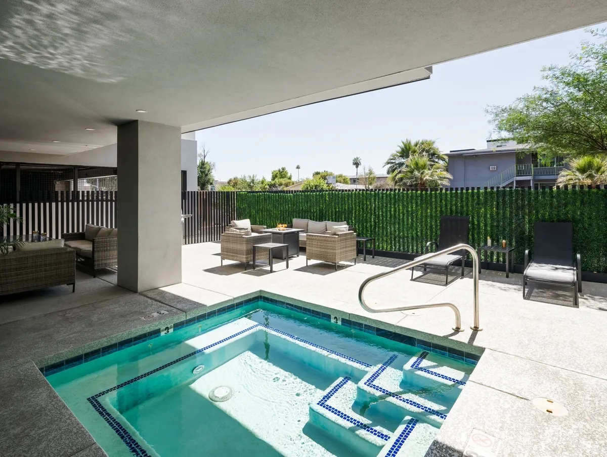 An inviting outdoor area with a bubbling hot tub, stylish seating, and lush green hedges. The space is ideal for relaxing in the sun or unwinding in the evening, with enough room for friends or family to gather comfortably.